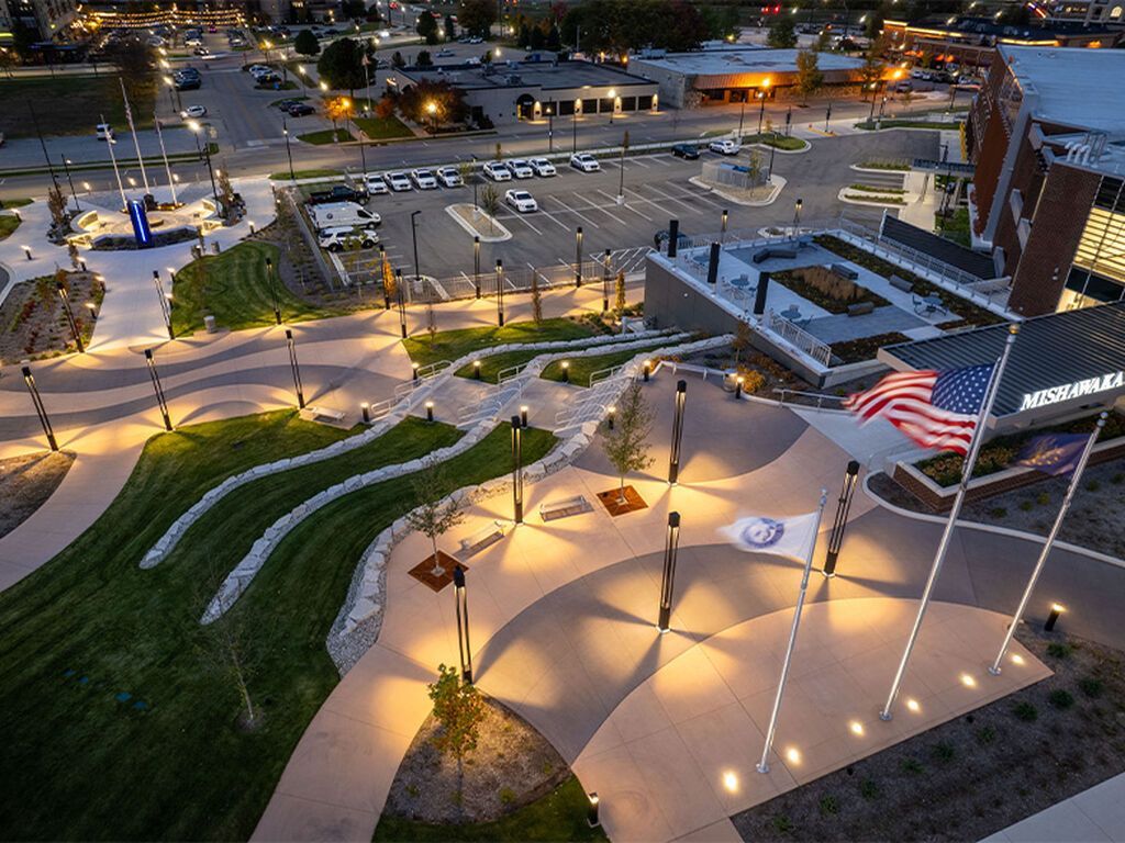 An elevated, night view of a landscaped park with glowing pathways, green areas.