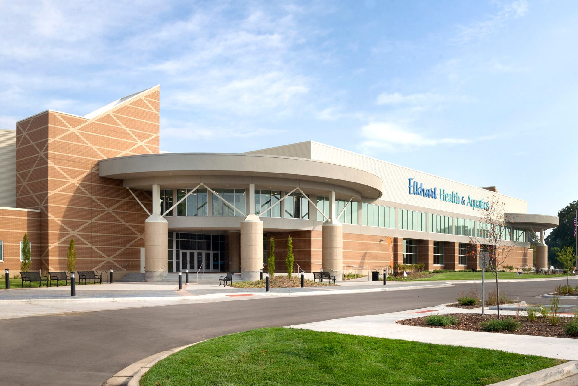 A modern brick and glass building with a circular entryway under a blue sky, featuring the sign 