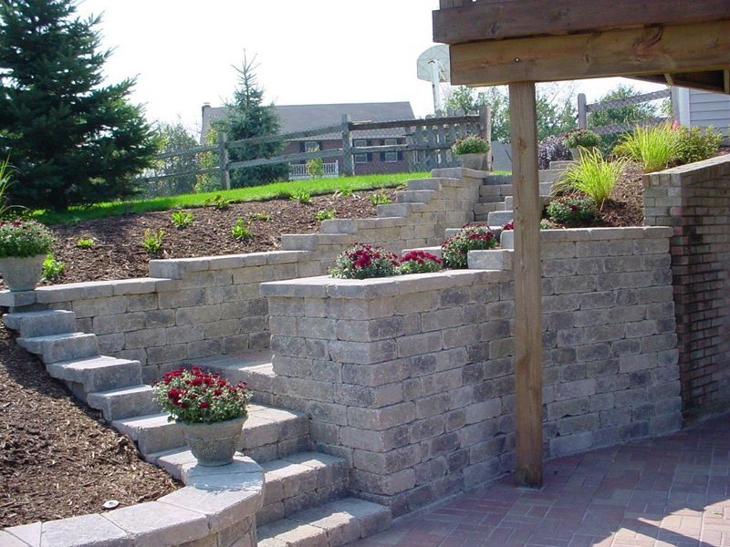 Stone steps and retaining walls with built-in planters lead up a sloped yard.