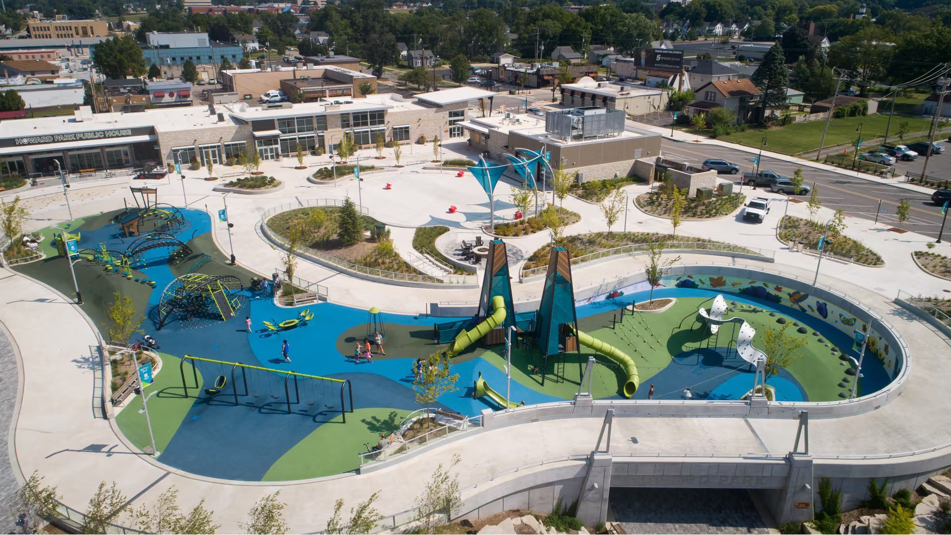 An aerial view of a colorful, modern outdoor playground with winding paths, play structures, and landscaping.