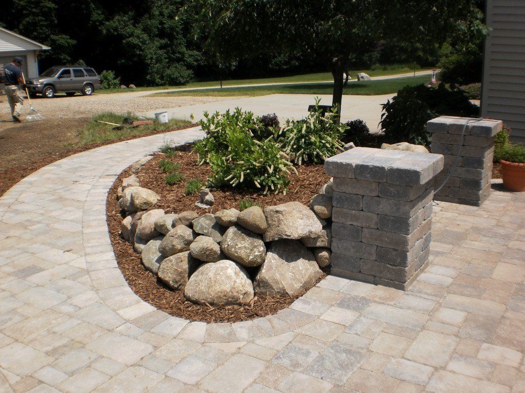 Stone pathway leads past a rock garden and pillars.