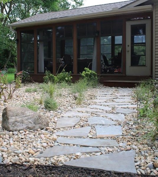 Stone path through a rocky garden leading to a screened porch with a door.