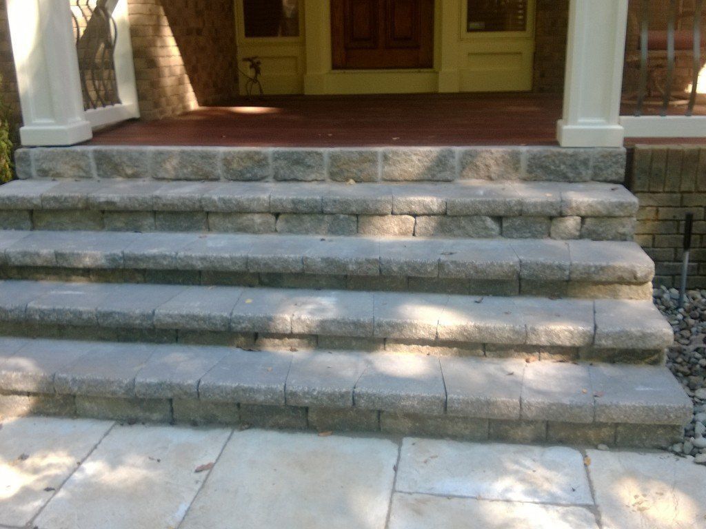 Stone steps leading up to a porch with a brown door.