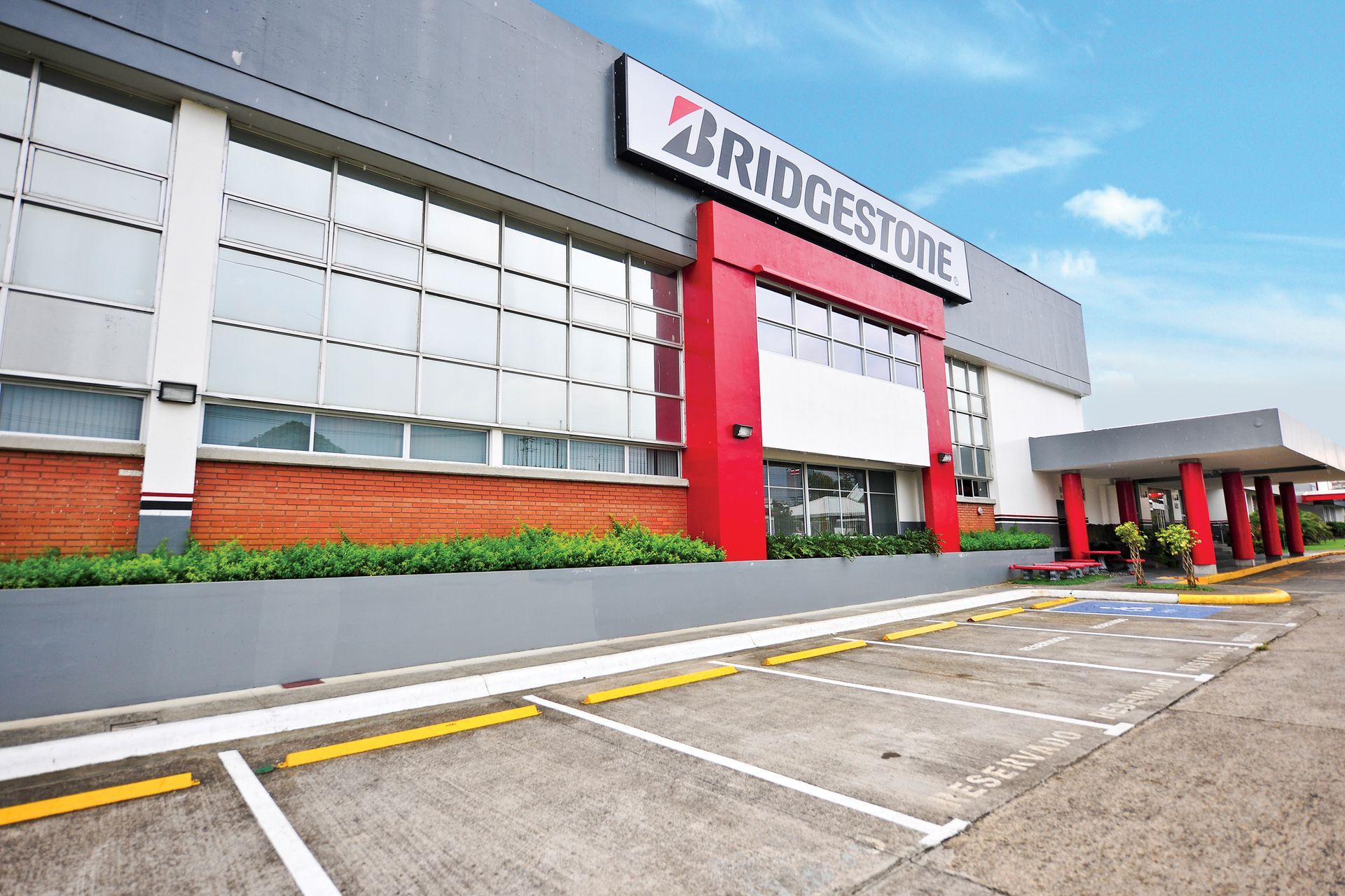 Bridgestone storefront with red entrance and parking lot under a blue sky