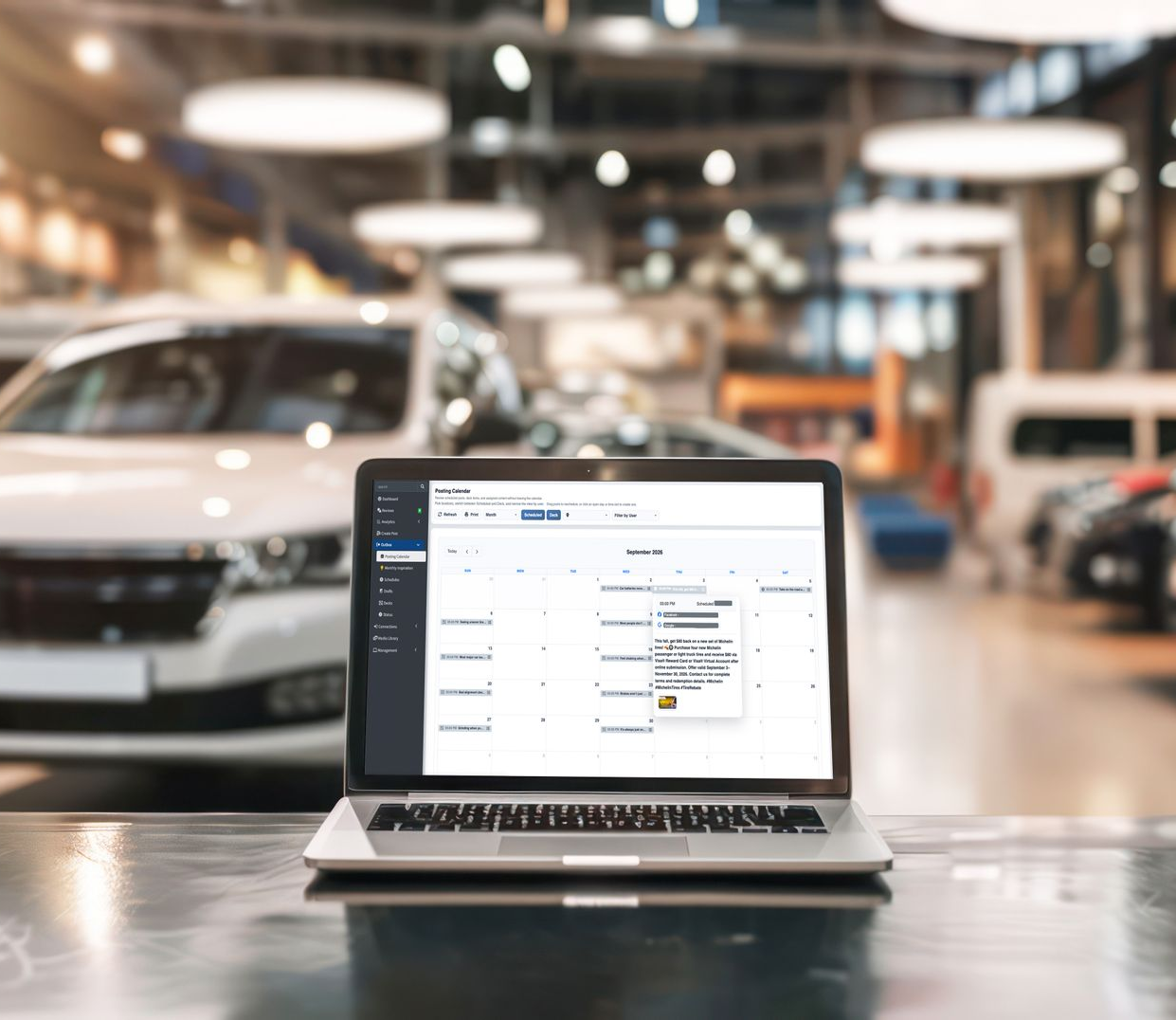 Laptop on a table in a car showroom, with vehicles blurred in the background.