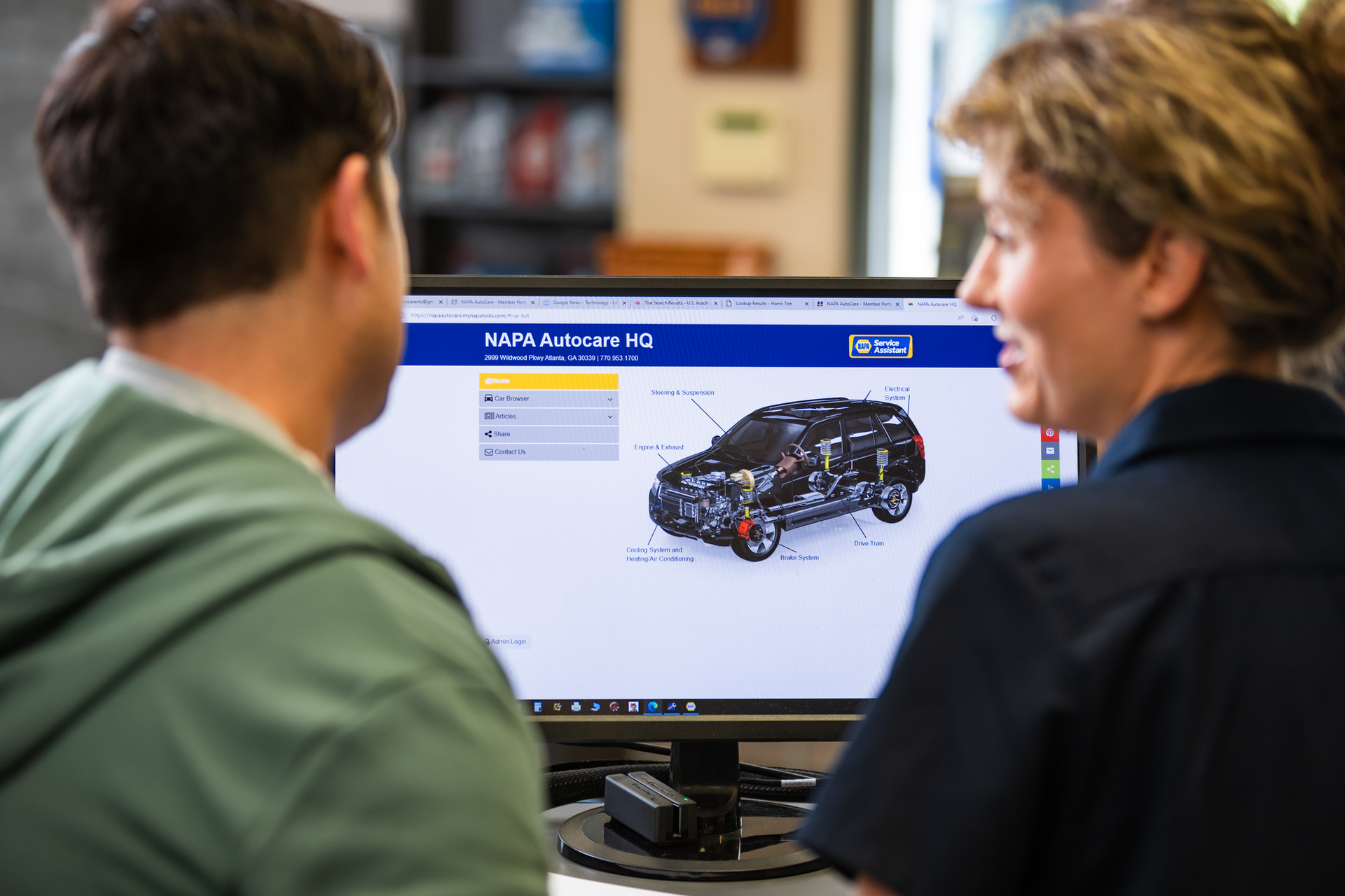 Two people viewing a car design on a computer screen in an office