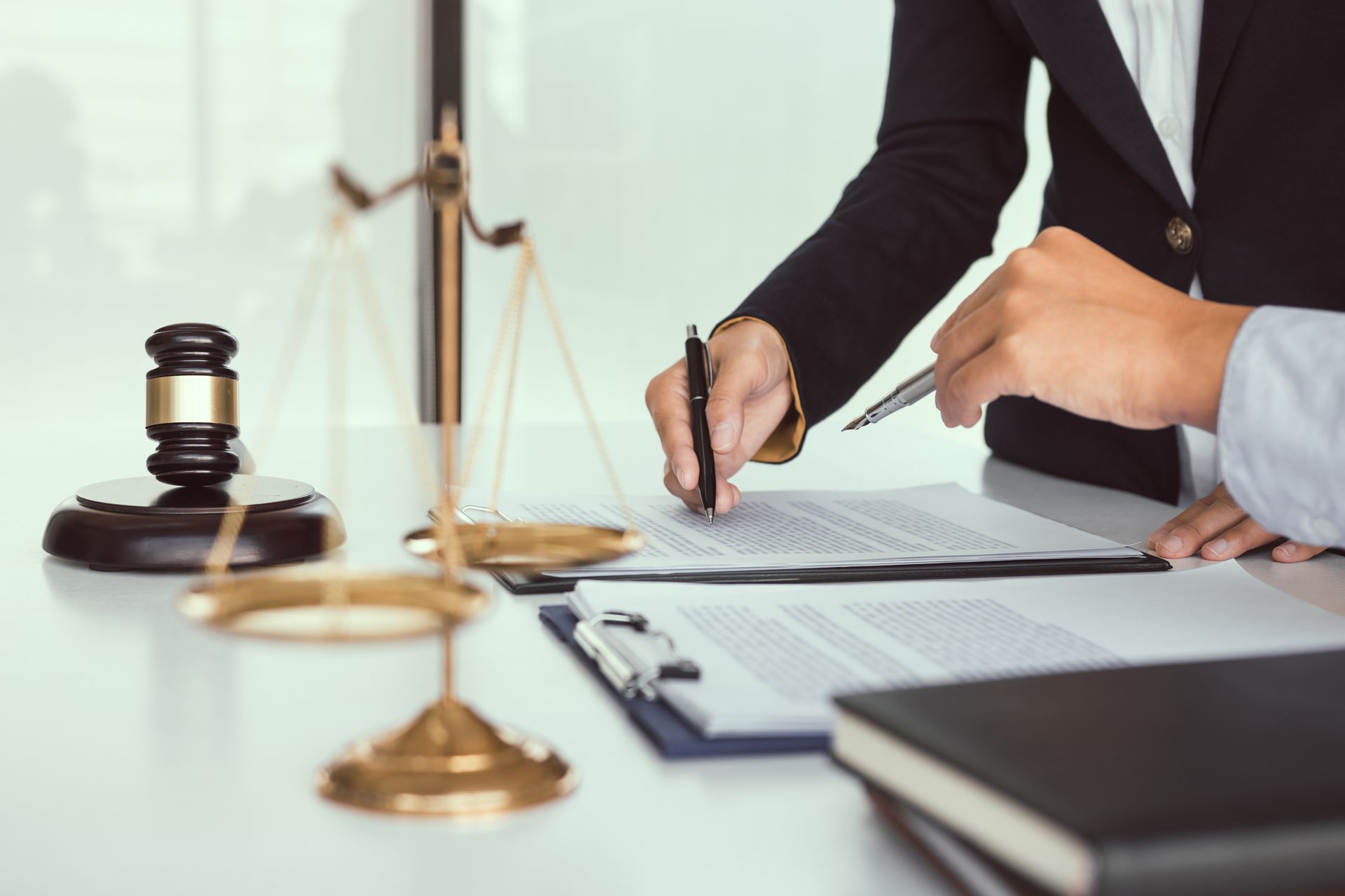 Lawyer signing a document beside a gavel and scales of justice in an office