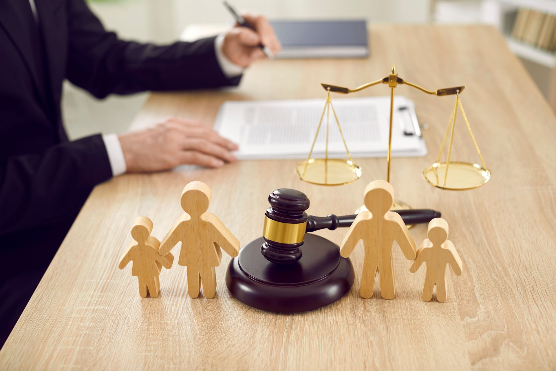 Justice scales and gavel beside paper family cutouts on a law office desk
