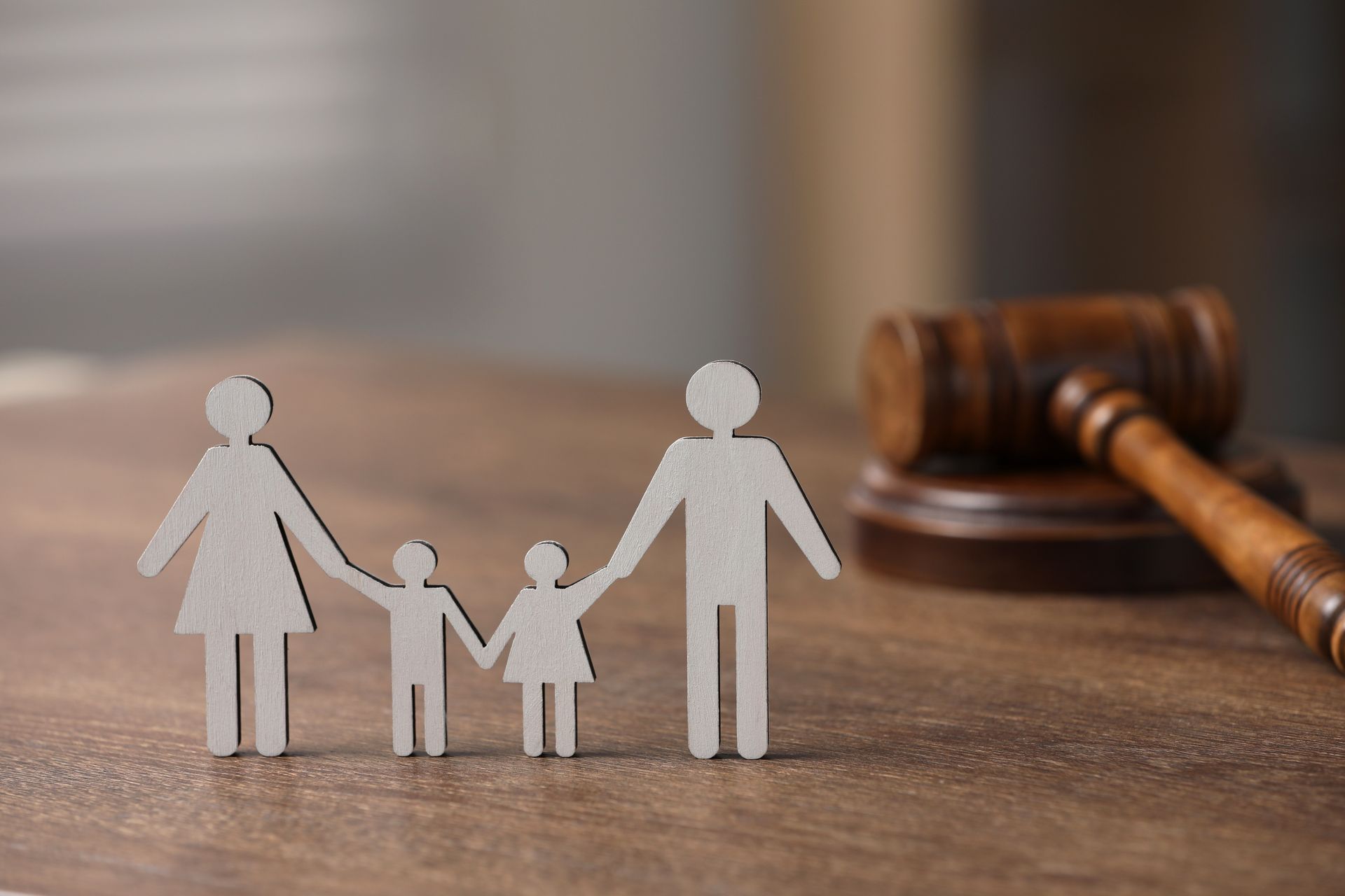 Paper family figures beside a gavel on a wooden table, suggesting family law or custody decisions