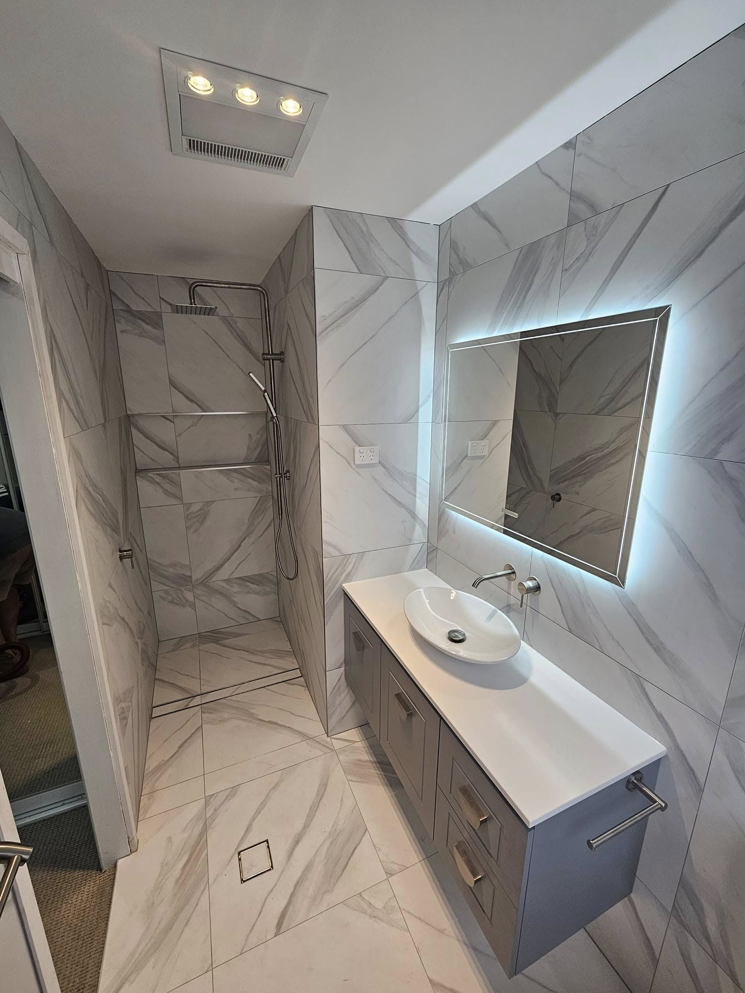 A bathroom with a sink , mirror and shower.