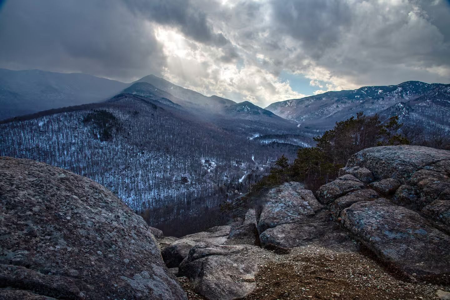 A view of a snowy mountain range from a rocky cliff.
