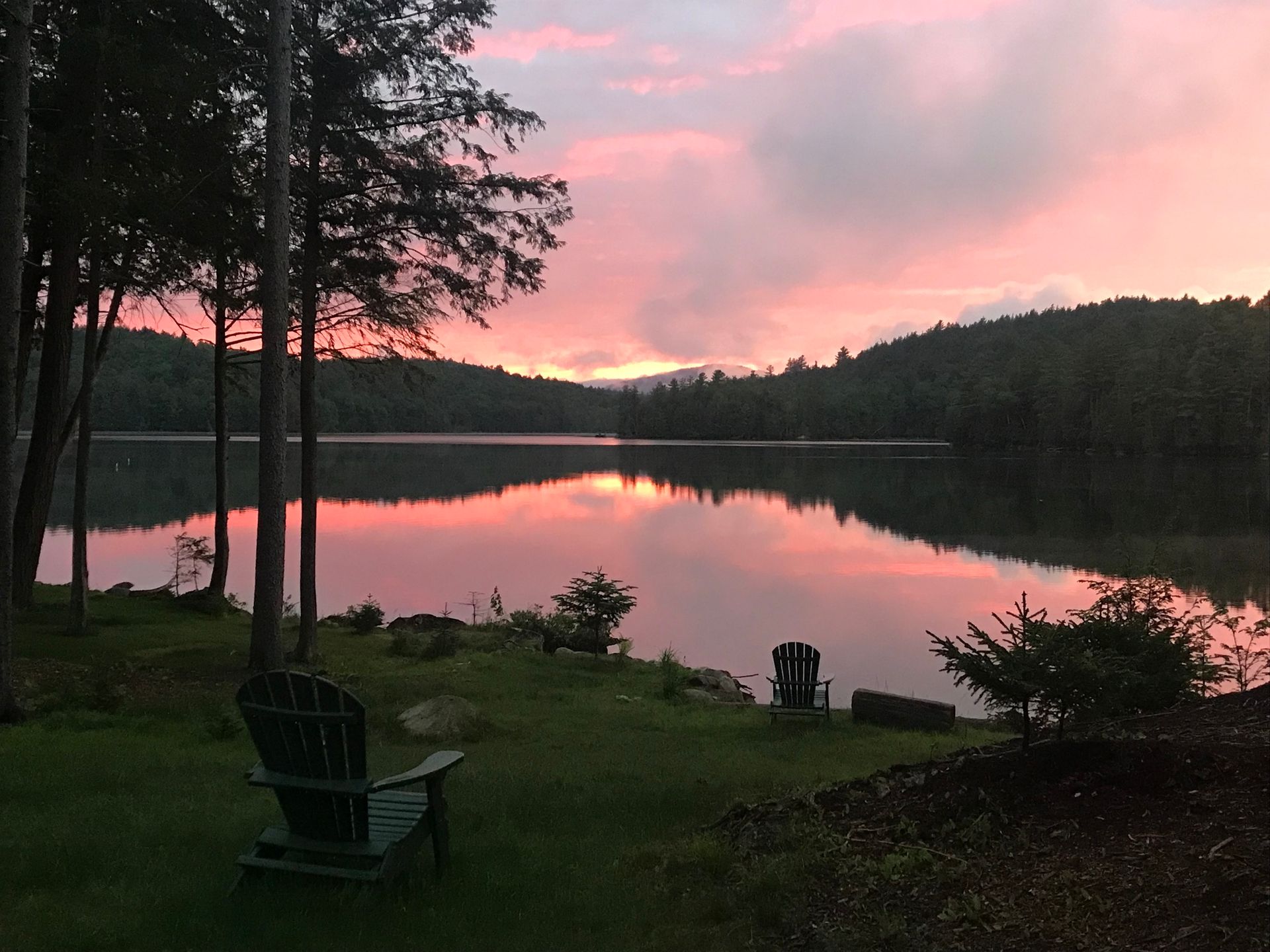 A sunset over a lake with a chair in the foreground