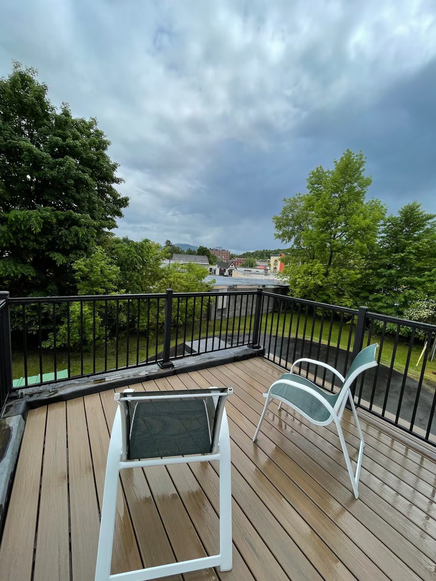 A deck with two chairs and a railing on a cloudy day.