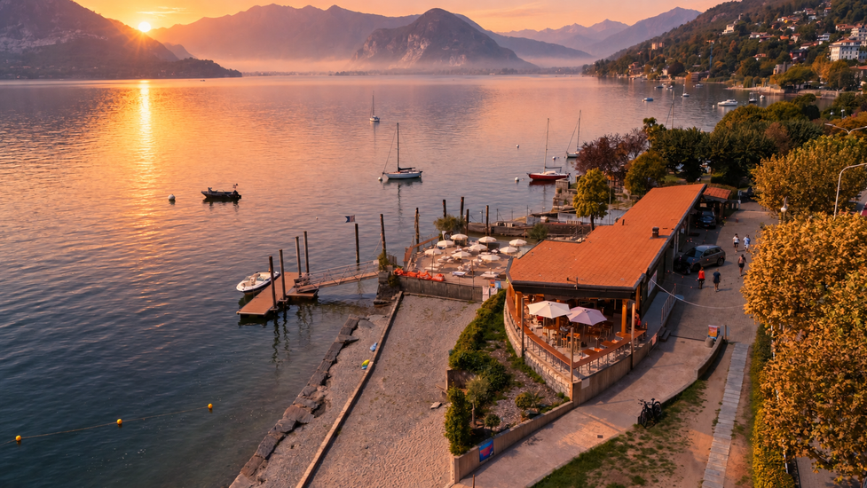 Persone su un molo in un lago al tramonto, con una rampa che conduce verso l'alto e montagne sullo sfondo.