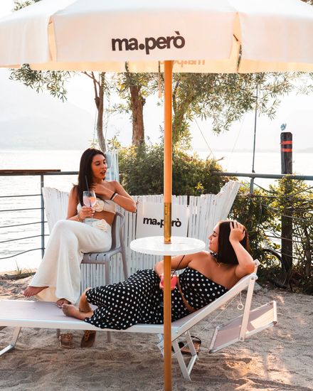 Barista che versa il liquido da una bottiglia blu in uno shaker di rame. Ambiente da bar sulla spiaggia.