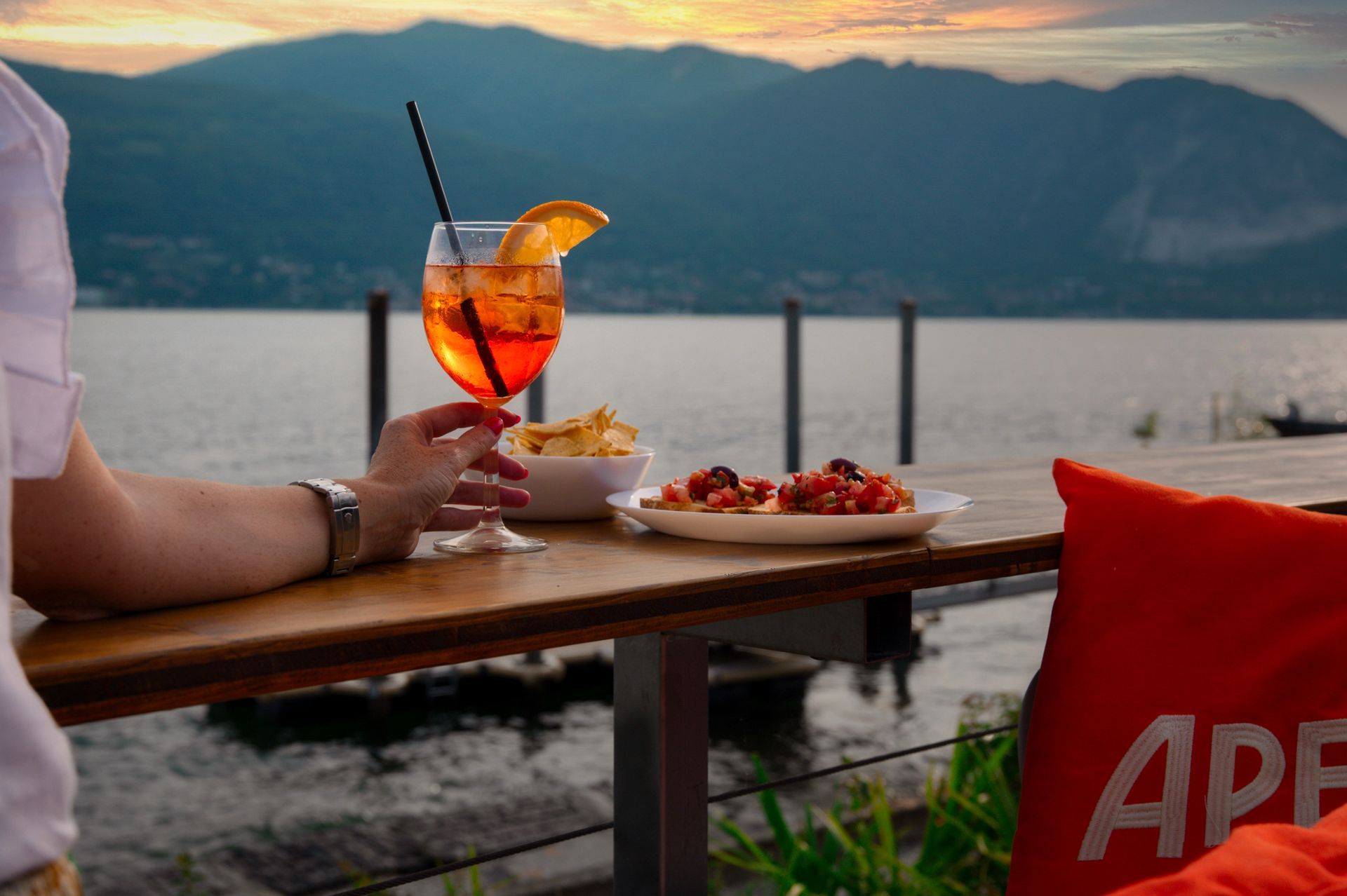 Un DJ suona musica durante un evento all'aperto. Un ragazzo indossa una maglietta nera ed è in piedi di fronte a un lago.