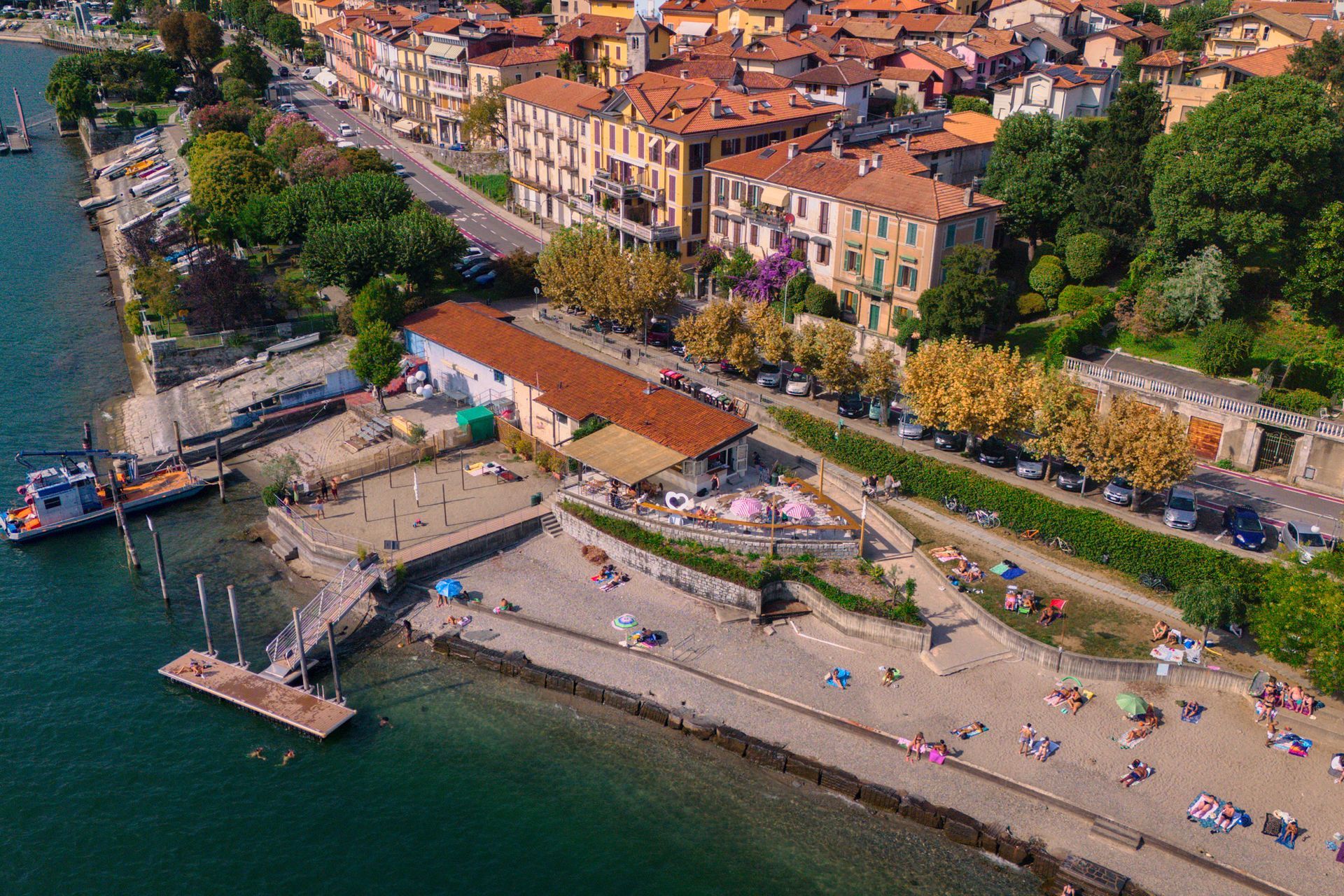 Una coppia si siede in un bar sul lungomare e sorseggia un drink, ammirando il lago e le montagne al tramonto.