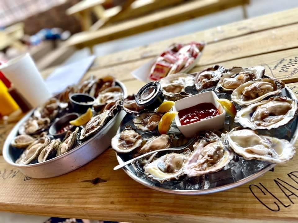 Two plates of oysters are sitting on a wooden table.