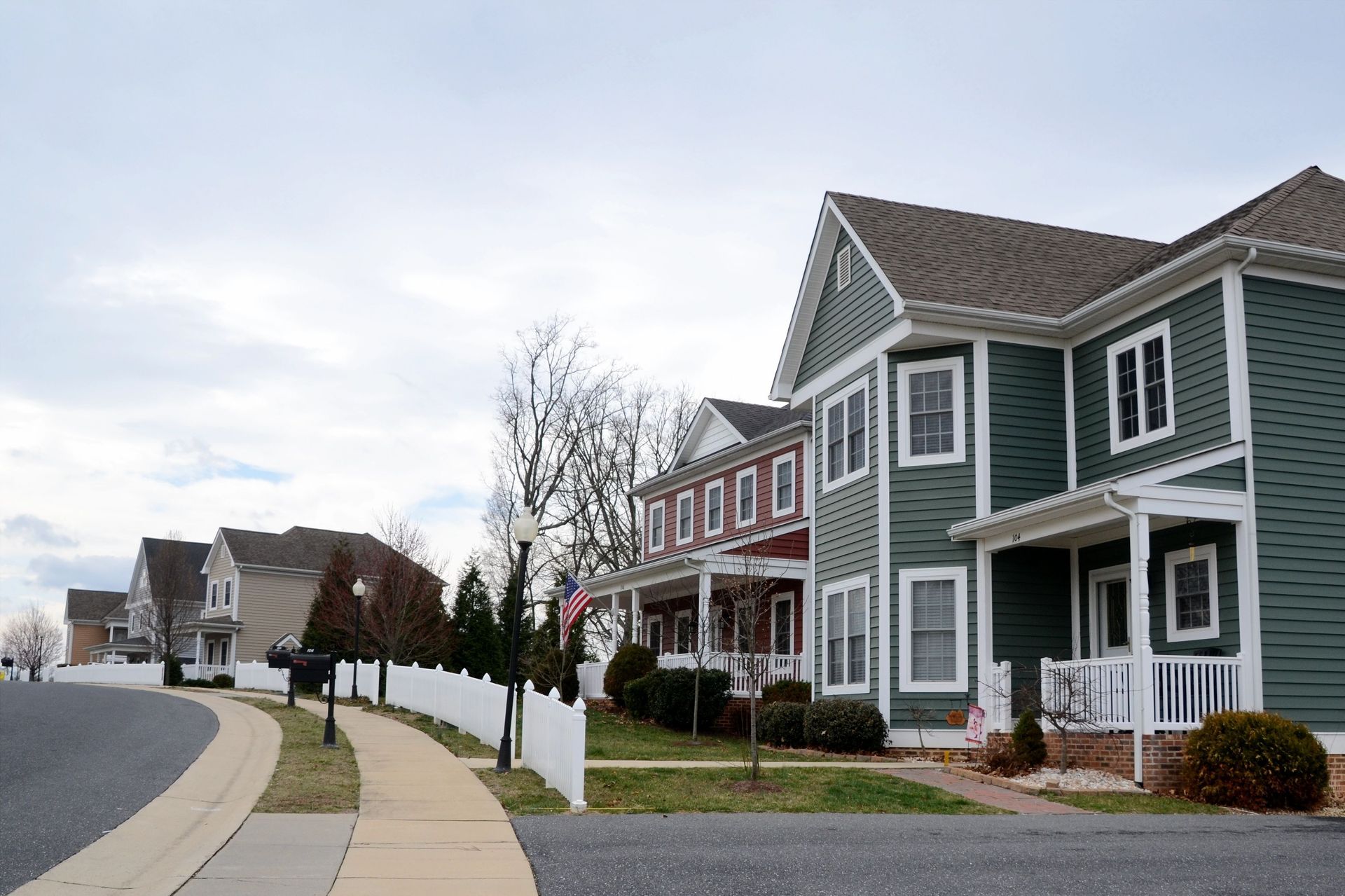 Quiet suburban street with row of modern townhouses and sidewalks under a cloudy sky