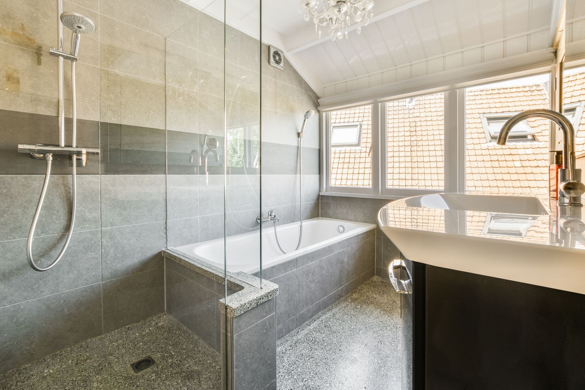 Modern bathroom with a freestanding tub, glass shower, and double sink under a sloped ceiling