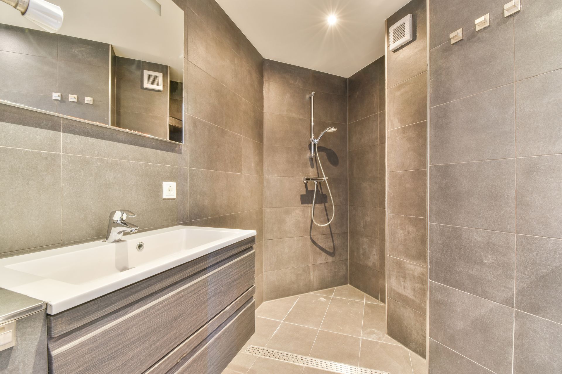 Modern bathroom with vanity, sink, mirror, and large walk-in shower in gray tile