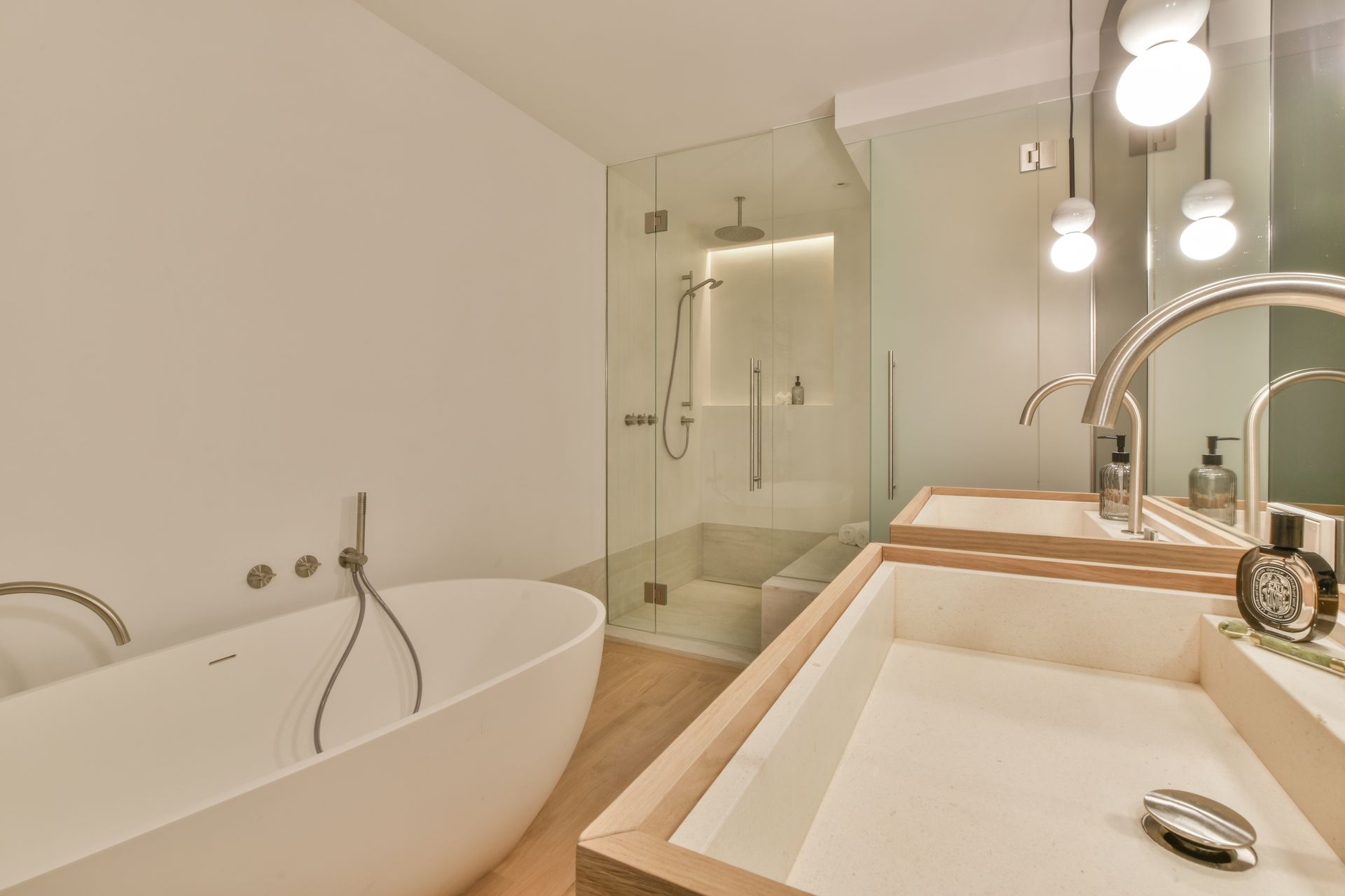 Modern bathroom with freestanding tub, glass shower, double sink vanity, and large mirror with lights
