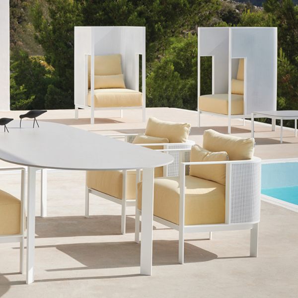 Un patio con sillas y mesas al lado de una piscina