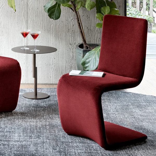 Una silla roja está colocada sobre una alfombra junto a una mesa con dos copas de martini.