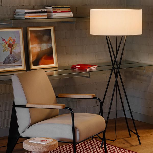 Una lámpara está sentada al lado de una silla en una habitación