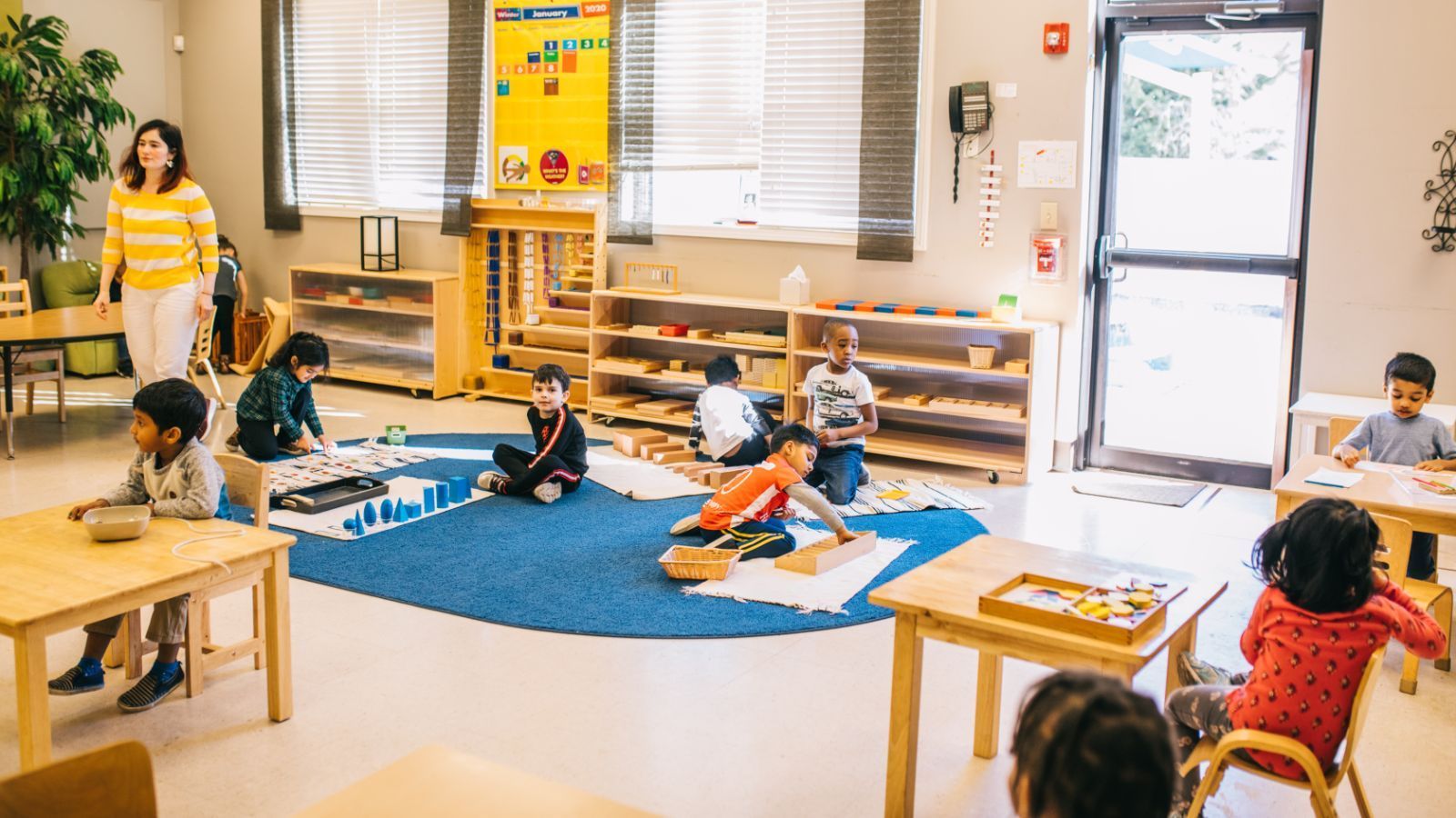 A group of children are sitting on the floor in a classroom.