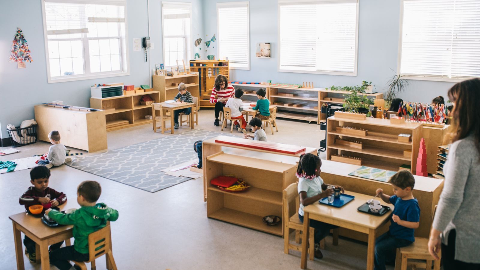 A group of children are sitting at tables in a classroom.