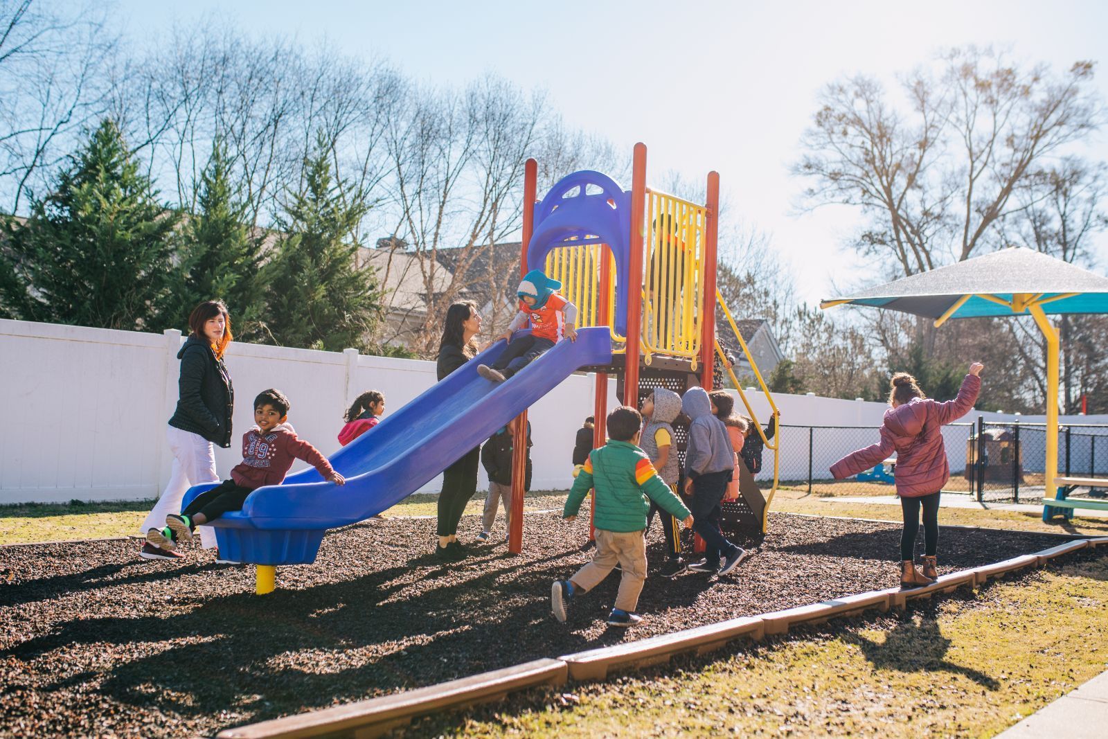 A group of children are playing on a slide at a playground.
