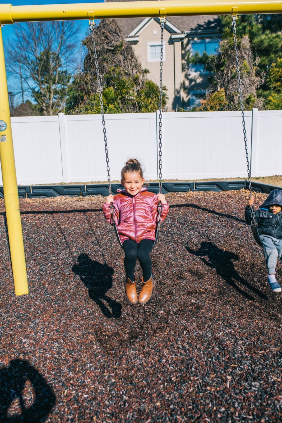 A little girl is sitting on a swing at a playground.