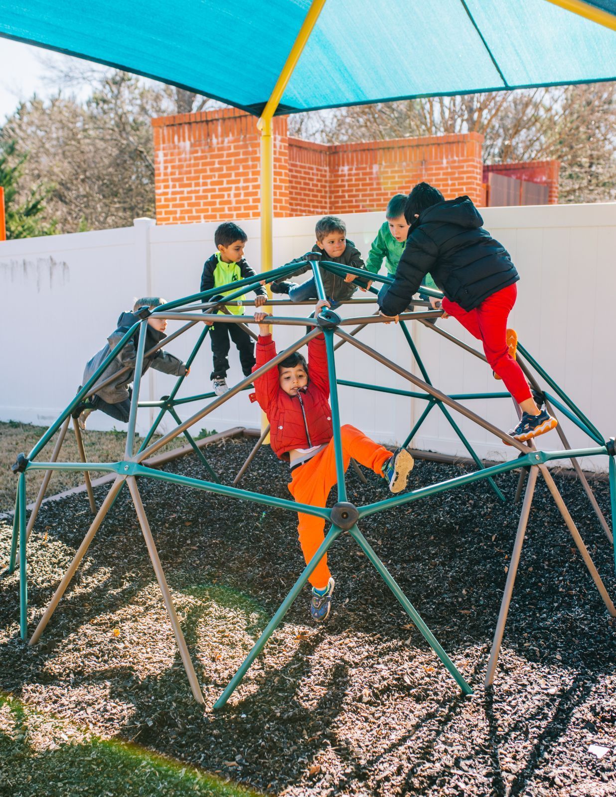 A group of children are playing on a climbing structure.