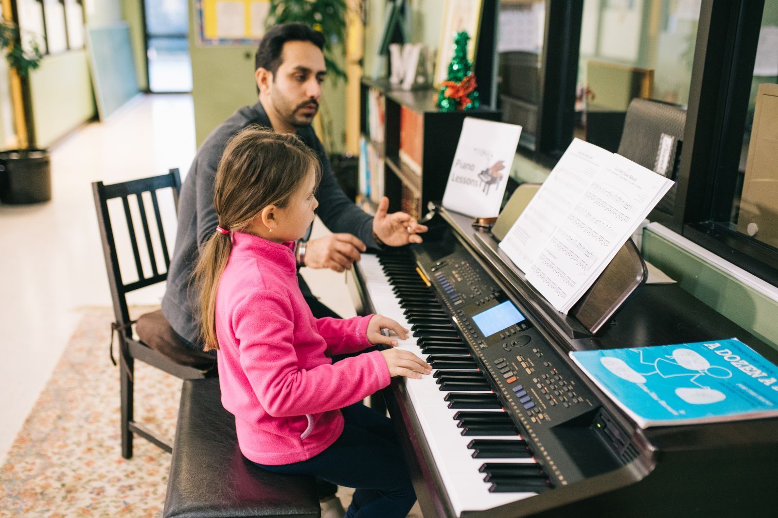 A man is teaching a little girl how to play the piano.
