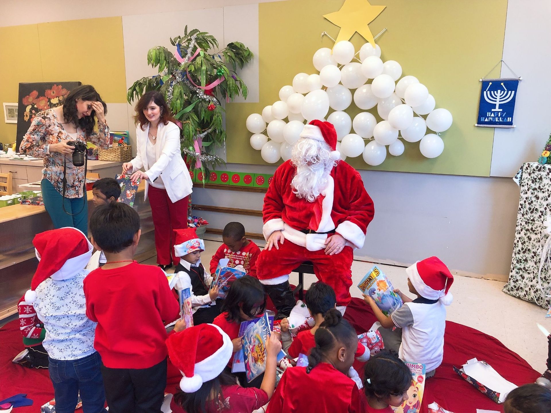A group of children are sitting around santa claus in a room.