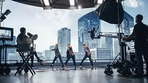 Three actors on a soundstage being directed and filmed