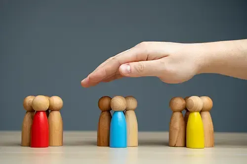 Hand shielding a group of employees represented by wooden figures of people