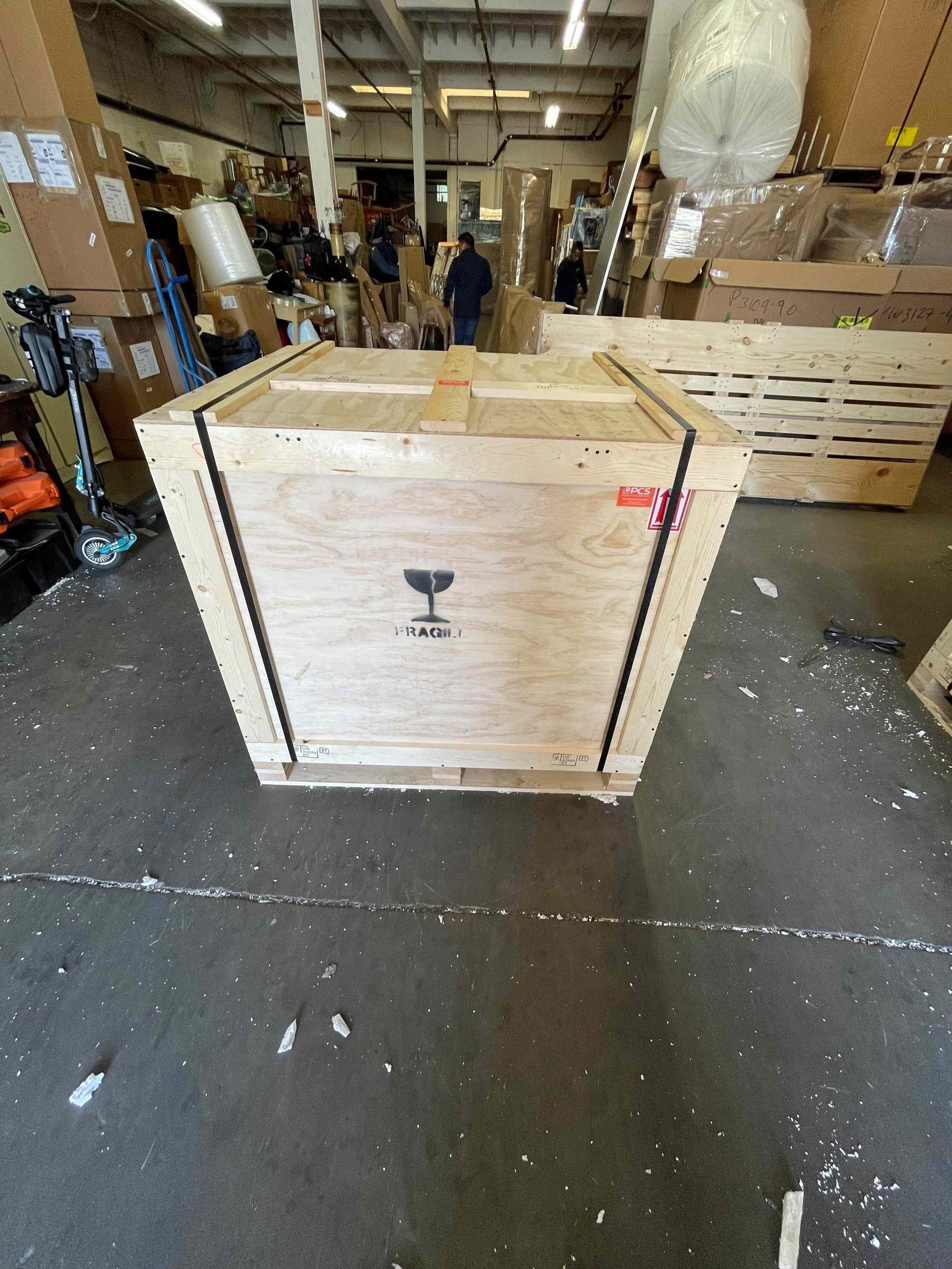 A large wooden box is sitting on the floor in a warehouse.
