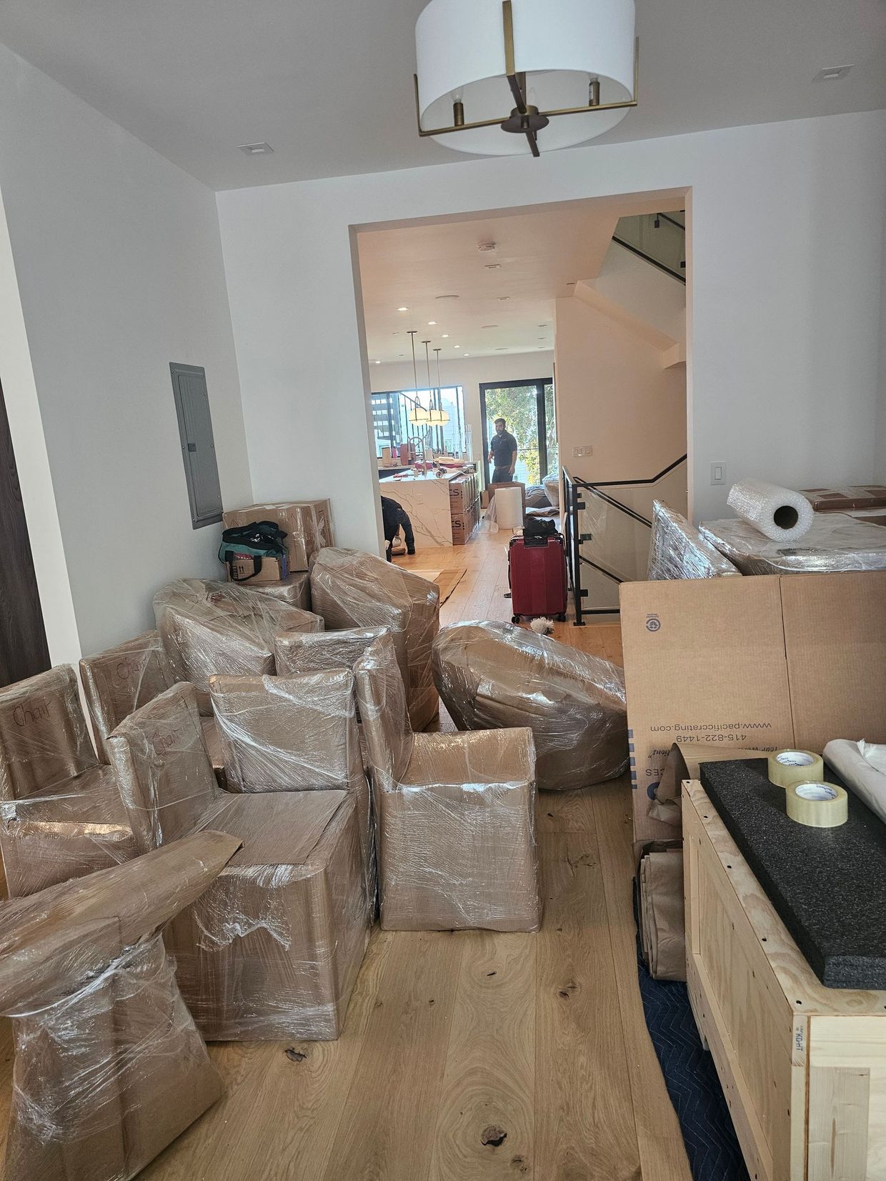 Living room filled with bubble-wrapped furniture and boxes, suggesting a move or renovation