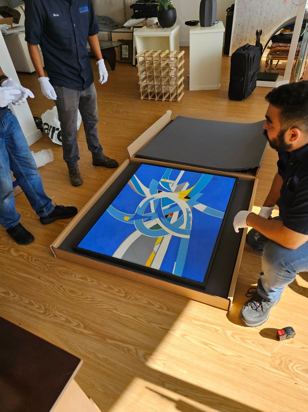 People gathered around a floor-mounted digital display showing a blue abstract design.