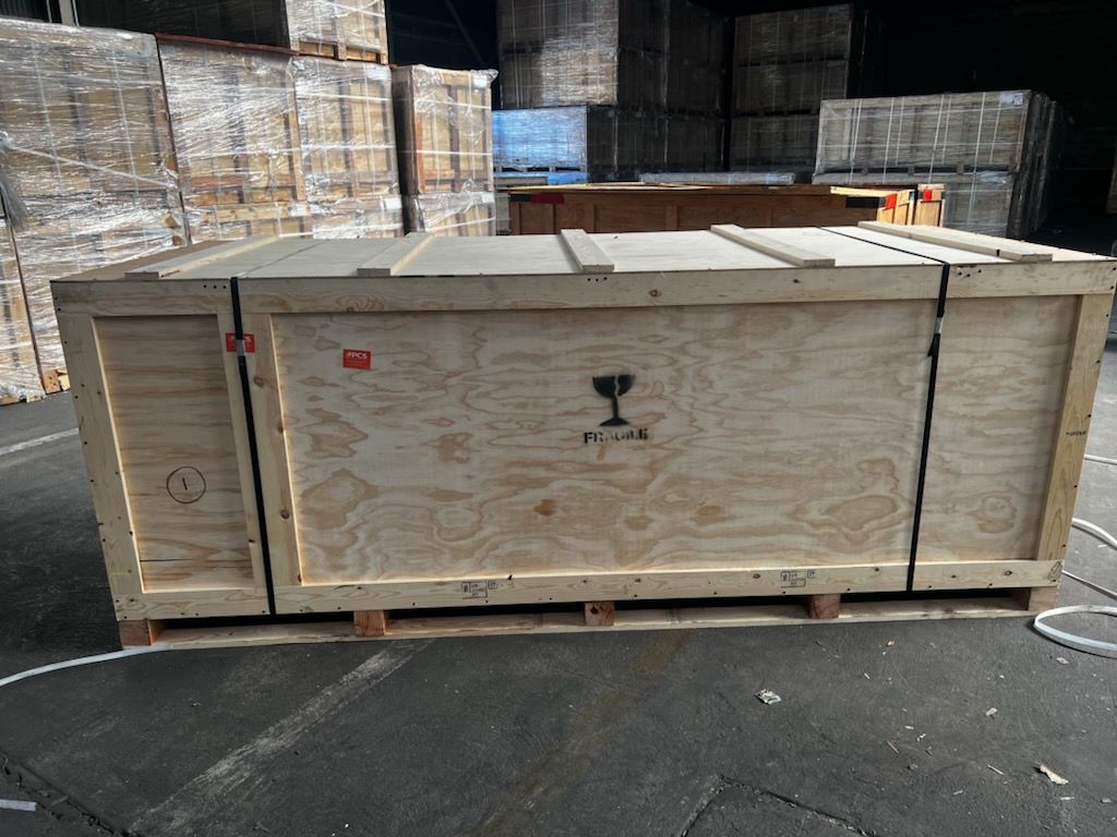 A large wooden box is sitting on top of a pallet in a warehouse.