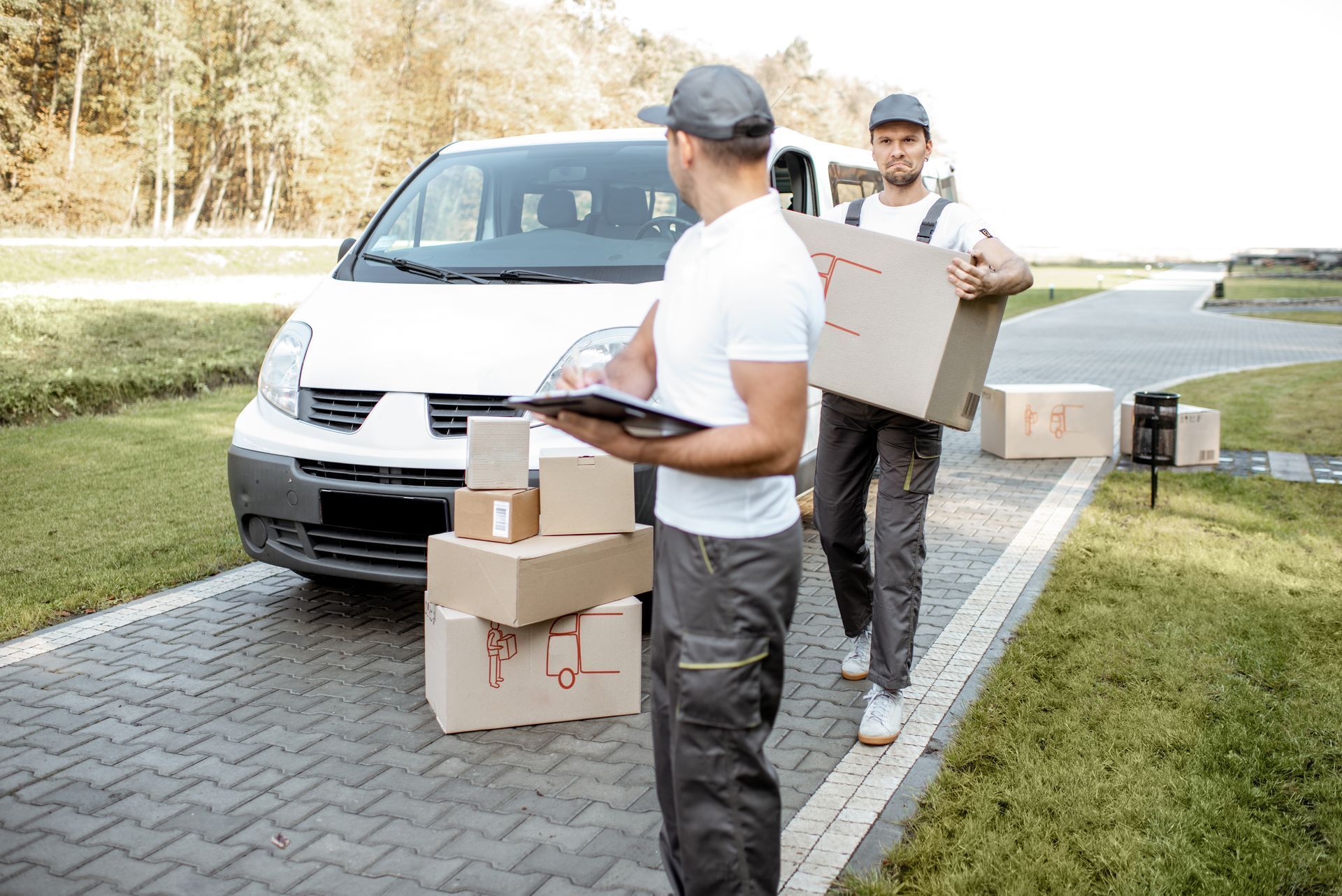 Two delivery men are loading boxes into a white van. Expert, timely interstate movers.