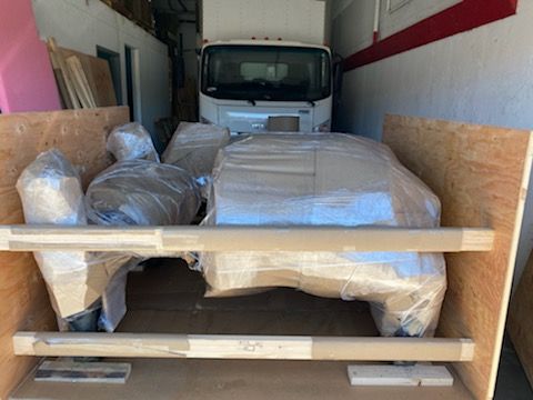 A truck is wrapped in plastic and sitting in a wooden crate. Timely delivery of heavy machinery shipping.