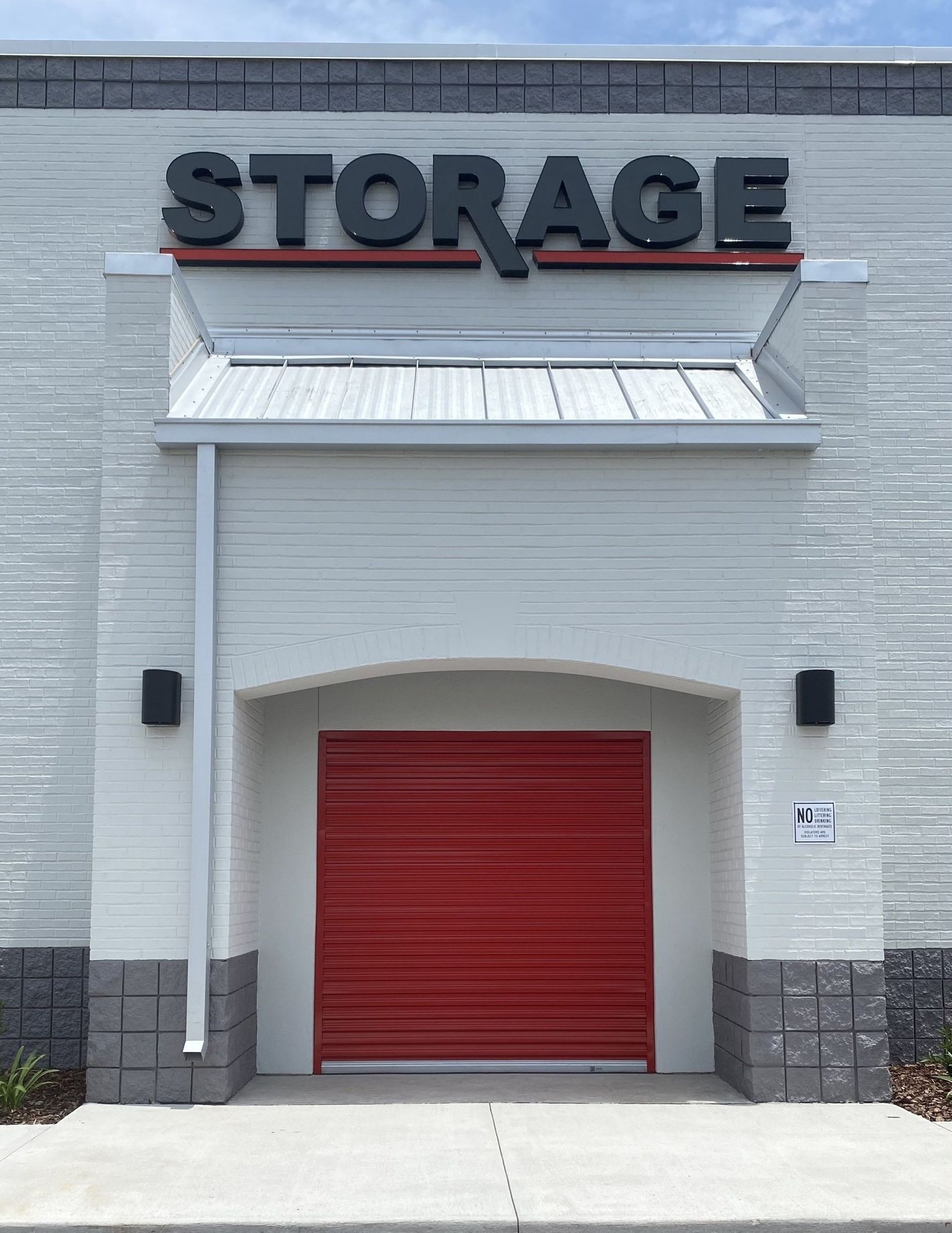 A white building with a red garage door and a sign that says storage