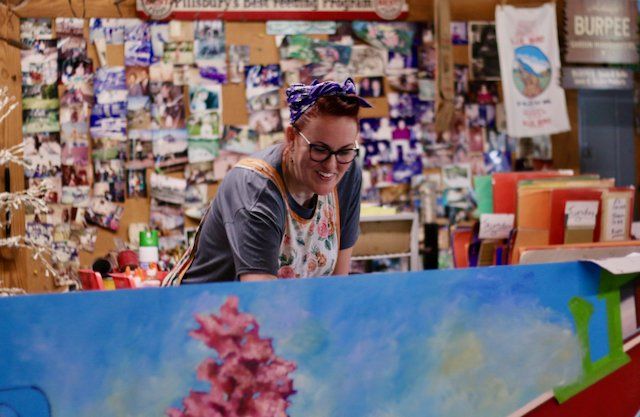 Photos of Elyse Johnson and her intern painting a mural of a train depot for the town of Angier, North Carolina