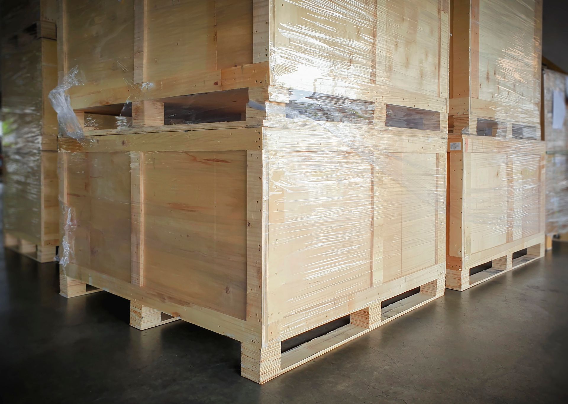 Grandi casse di legno per la spedizione avvolte in plastica trasparente all’interno di un magazzino