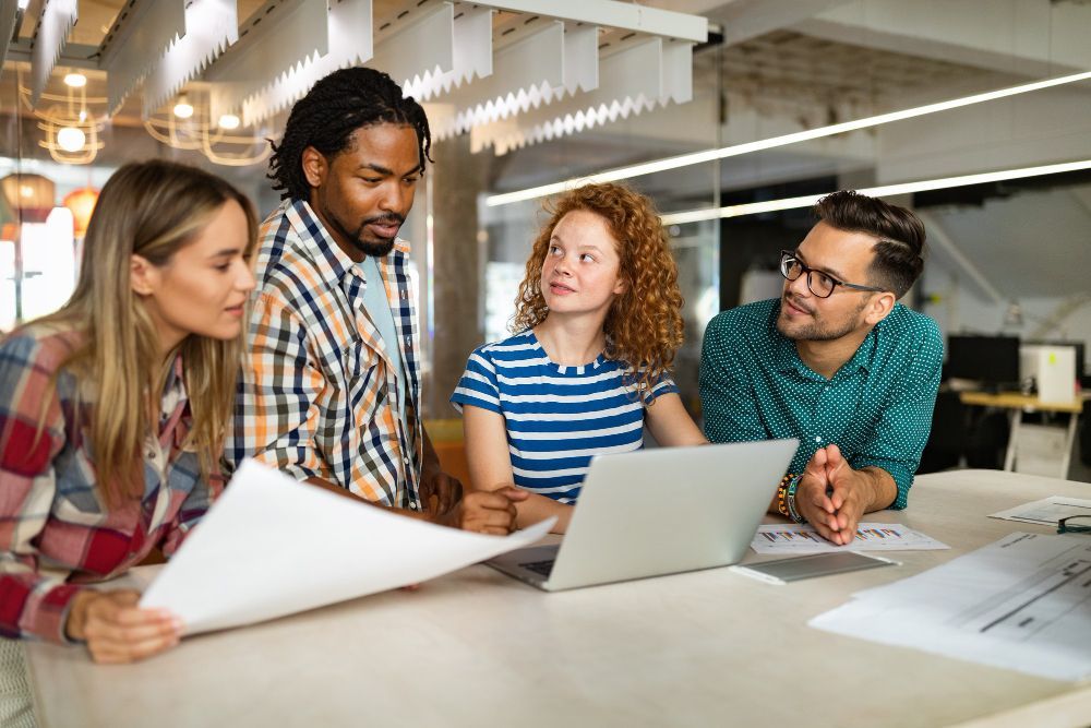 Un groupe de personnes sont assises autour d'une table et regardent un ordinateur portable.