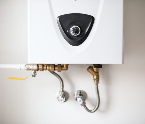 A white water heater with brass pipes attached to it