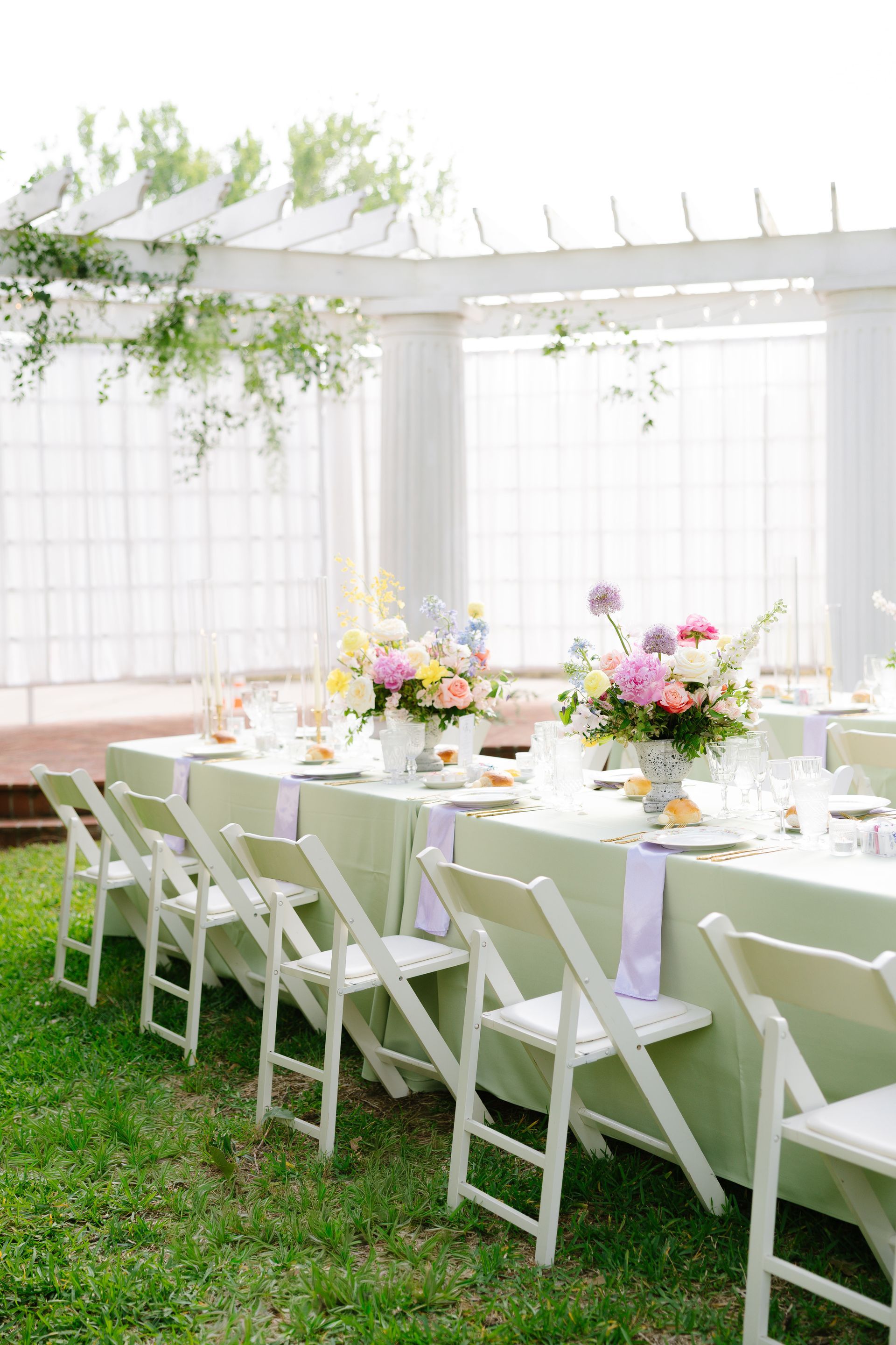 A large garden with tables and chairs set up for a rehearsal dinner party